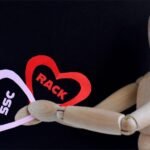 a wooden mannequin holding two signs reading SSC and RACK